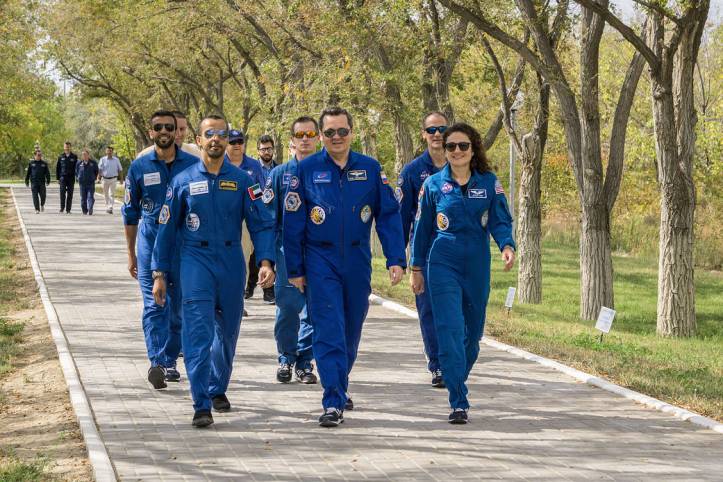 jsc2019e053724 - At the Cosmonaut Hotel crew quarters in Baikonur, Kazakhstan, spaceflight participant Hazzaa Ali Almansoori of the United Arab Emirates (left), Oleg Skripochka of Roscosmos (center) and Jessica Meir of NASA (right) lead the way down the W